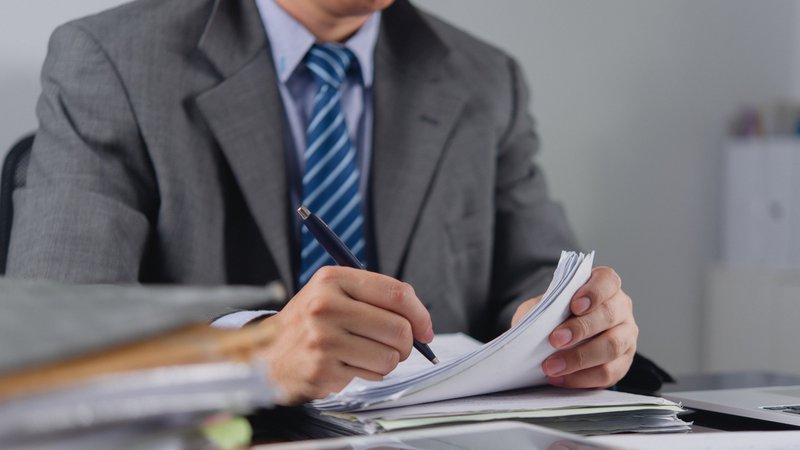 Business professional reviewing loan and financial documents at a desk.