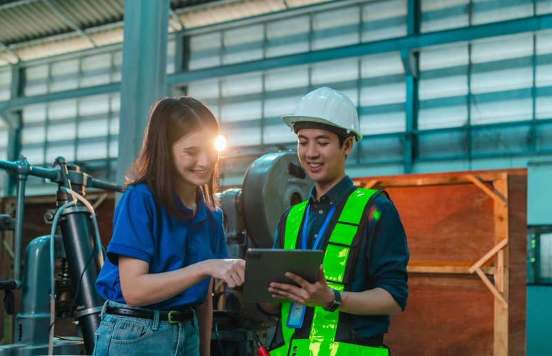 Manufacturing professionals reviewing production operations and industrial equipment on a tablet