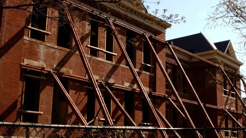A historic red brick building braced with metal supports, updated for Built Environment Sustainability.