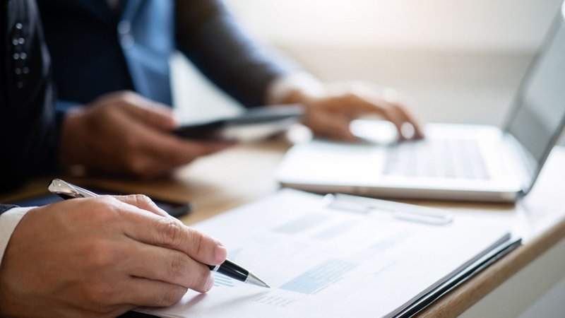 A person reviewing property documents and a laptop during a meeting for Zoning Consulting Services.