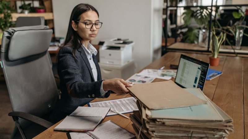 A municipal employee sitting at a desk organizing paperwork for NYC Building Permits.