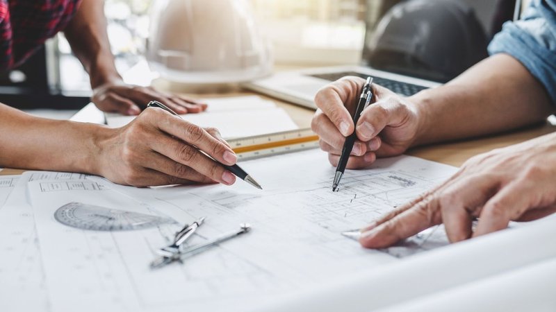 Two professionals reviewing architectural blueprints to apply for Building Permits NYC.
