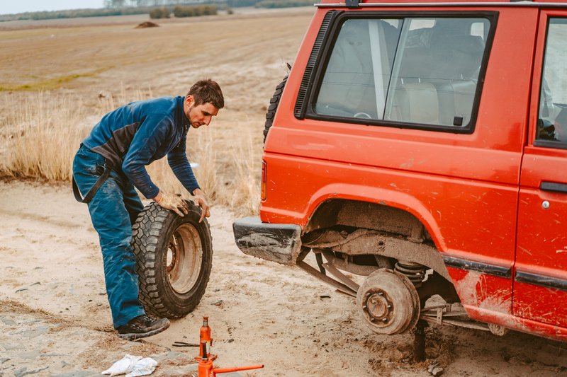 Man change the wheel manually on a 4x4 off road truck on the road