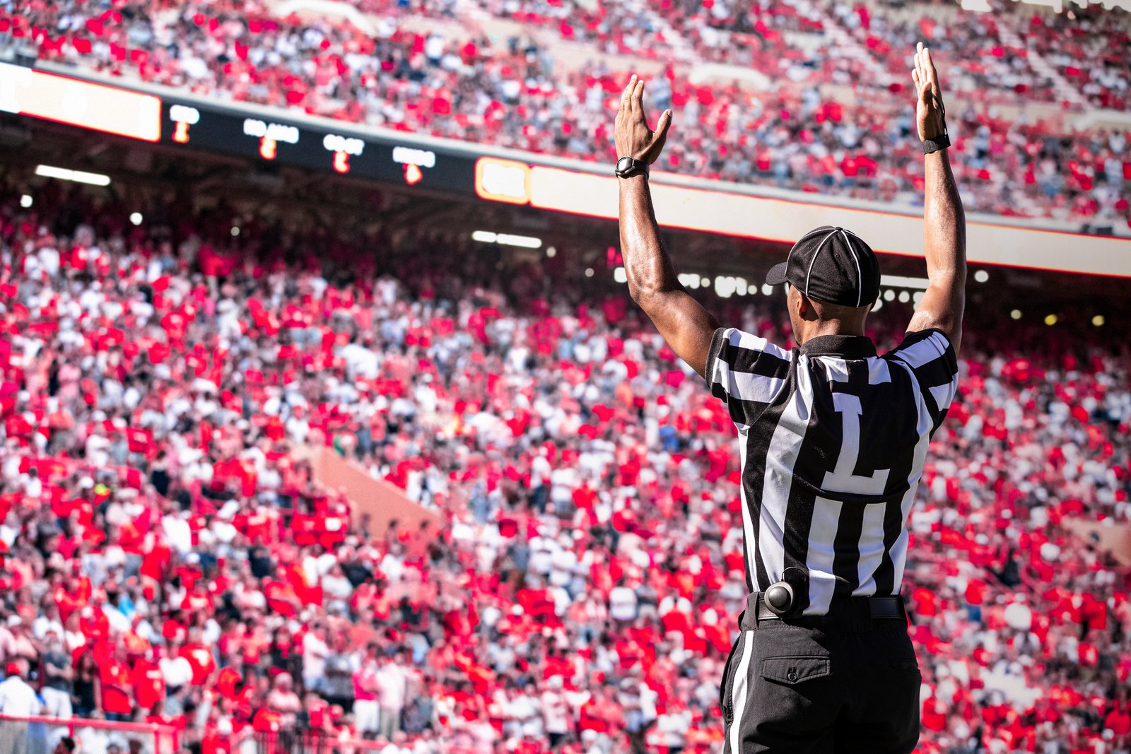 Packed college football stadium on game day, where campus police and medical teams coordinate through shared incident management