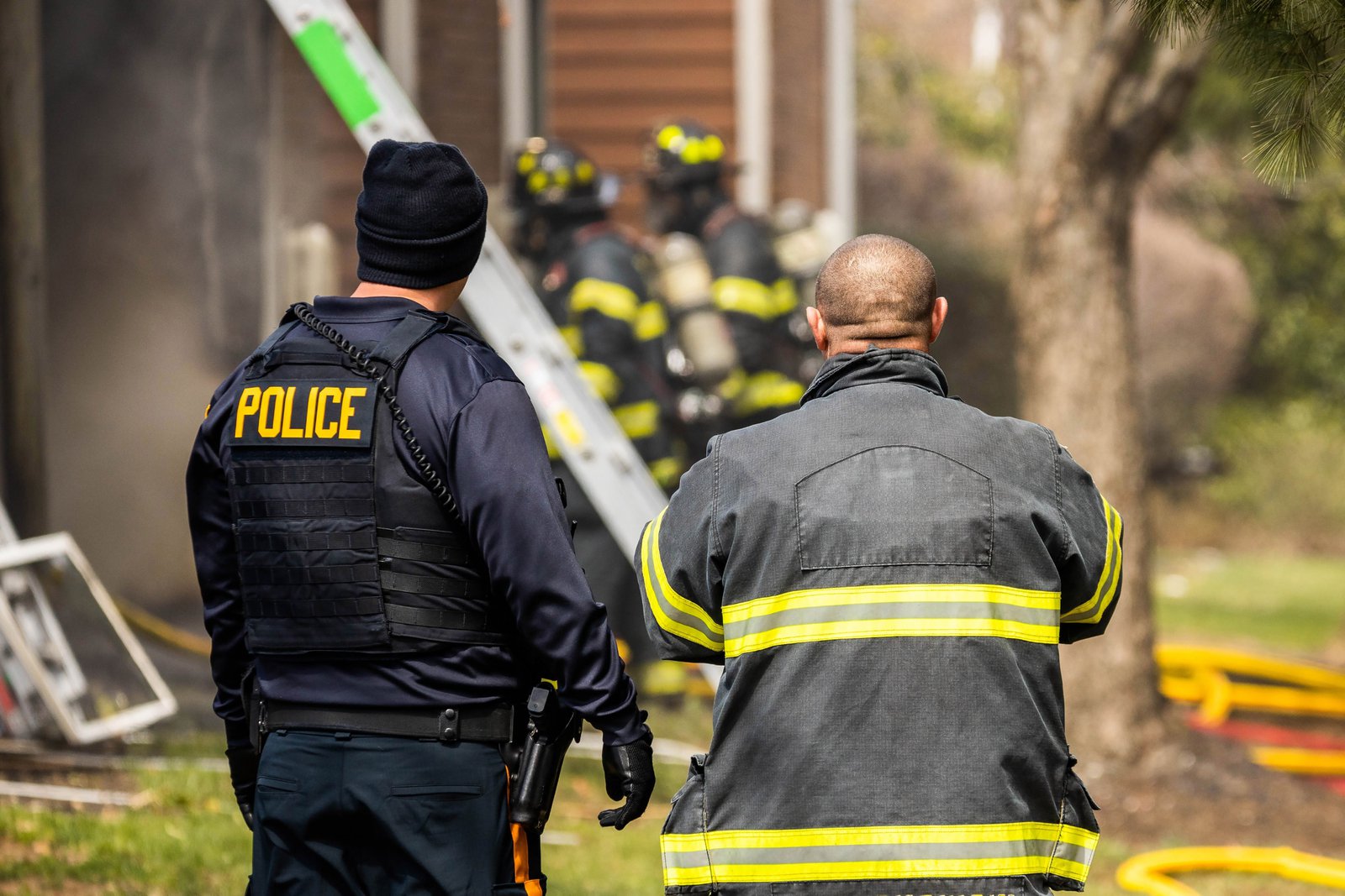 Police officer and firefighter coordinating at a house fire scene under the national incident management system