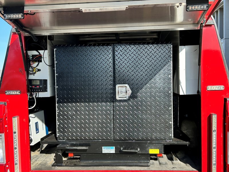 Locked diamond-plate storage cabinet on an Extendobed slideout with a load capacity label