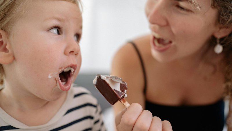 Un enfant mange une glace avec sa maman.