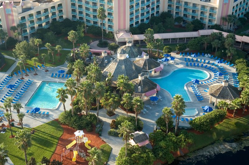 Vue aérienne d'un grand hôtel avec plusieurs piscines, une aire de jeux et des arbres tropicaux