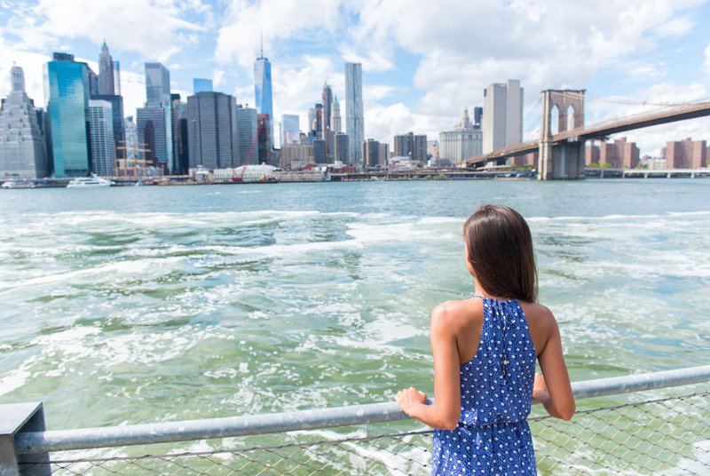 Une jeune fille contemple les gratte-ciel de l'autre rive depuis la rive