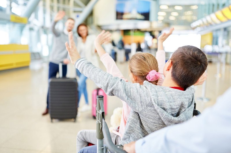 vliegvakantie - kinderen en ouders zwaaien naar elkaar in de luchthaven