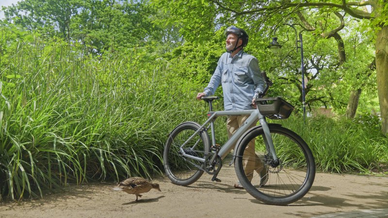Un canard s'approche d'un homme à vélo dans un parc verdoyant