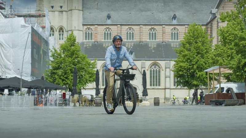 Un homme traverse la place d'une ville sur un vélo urbain Raleigh One