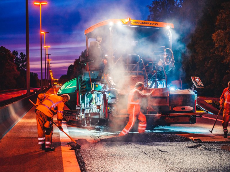 chantier le long d'autoroutes flamandes - travaux d'asphaltage au coucher du soleil.