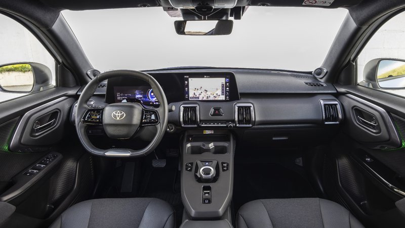 "Intérieur du Toyota Urban Cruiser : volant multifonction, combiné numérique et grand écran tactile central affichant la navigation."