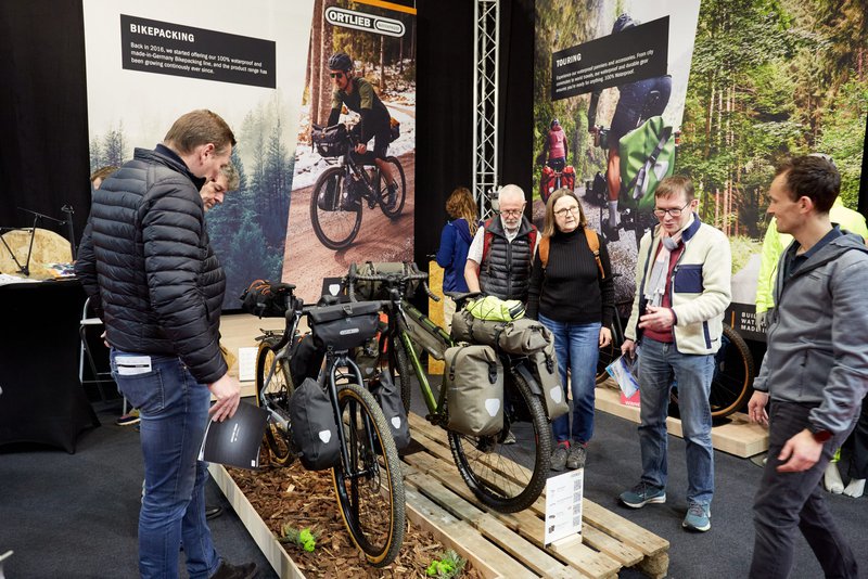 Bezoekers van de Velofollies beurs kijken naar twee gravelbikes met fietsbagage
