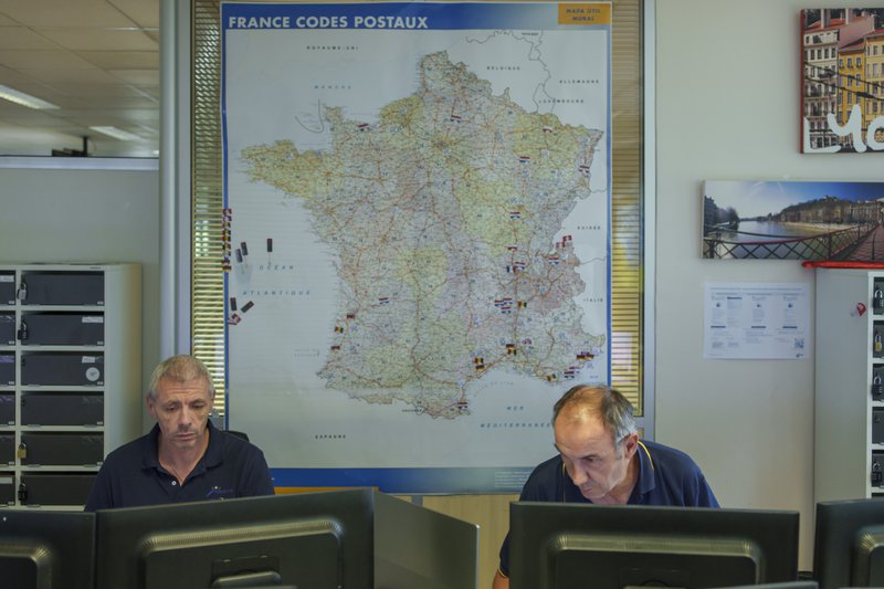 deux hommes devant leur ordinateur, avec une carte de France en arrière-plan.