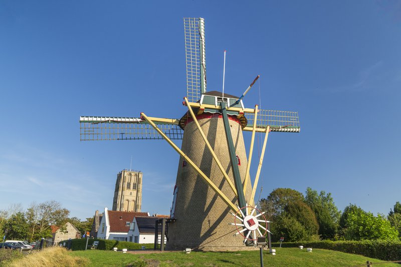 Goeree-Overflakkee, Pays-Bas: Moulin à vent et clocher en arrière plan, sur fond de ciel bleu.