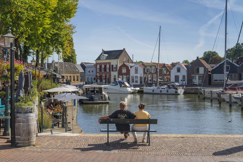 un couple assis sur un banc au bord de l'eau à Goeree-Overflakkee.