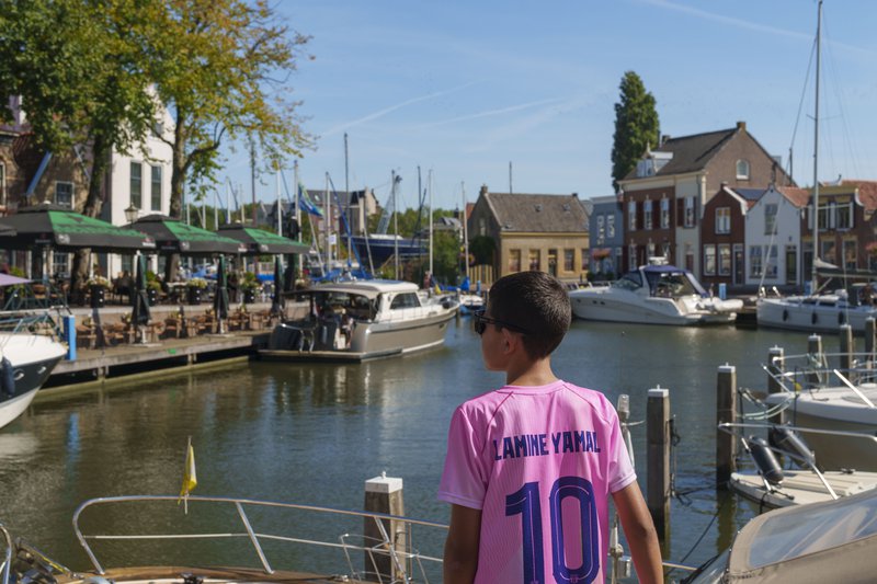 Personne devant un petit port de plaisance ensoleillé.