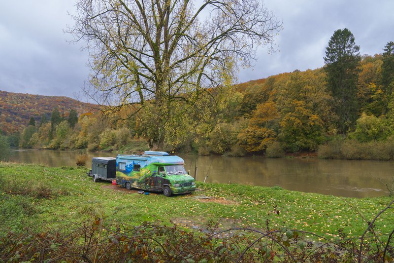 Camping-car garé sur la rive d'un fleuve.