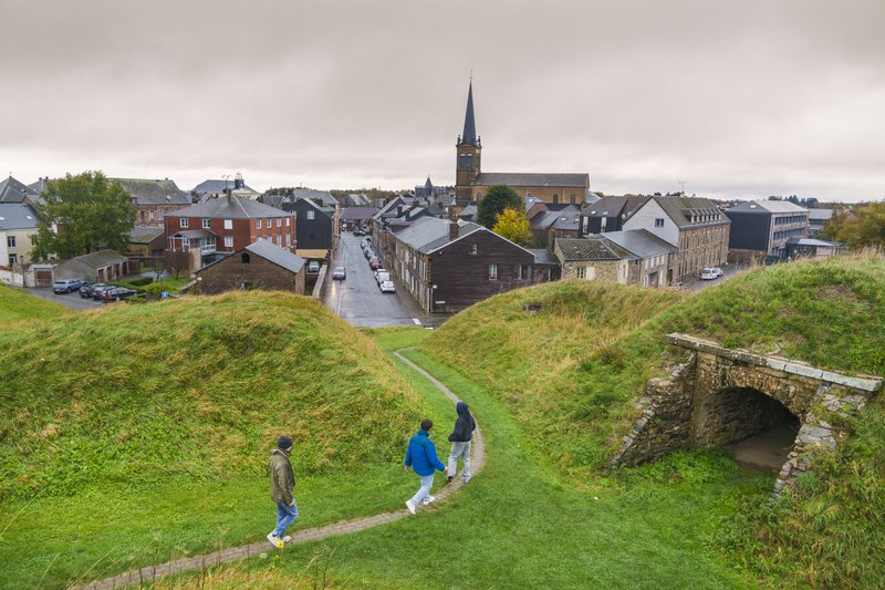 Petit village avec clocher et randonneurs dans les Ardennes françaises.