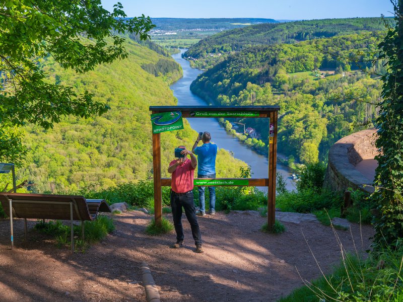 mensen fotograferen vanaf een heuvel een dieper gelegen rivier omgeven door bossen