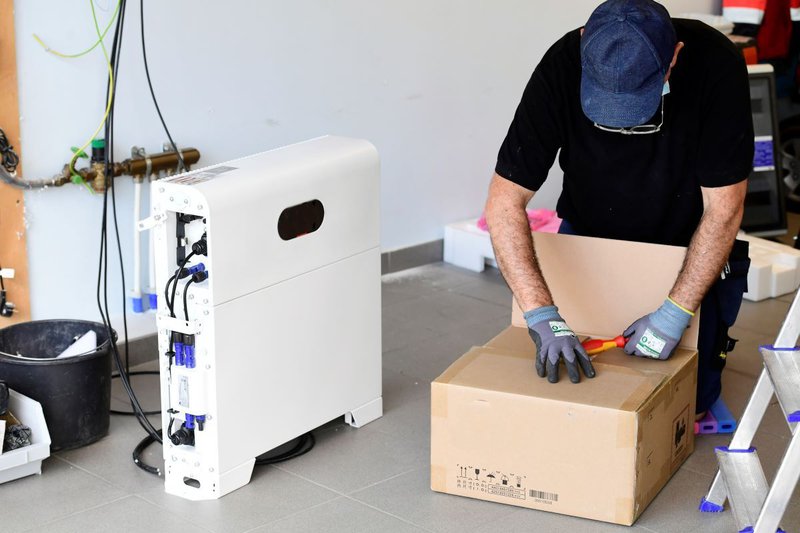 installateur naast een thuisbatterij in een garage