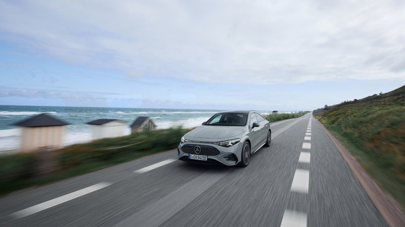 Mercedes-Benz CLA 250e gris roulant sur une route côtière avec l’océan en arrière-plan.