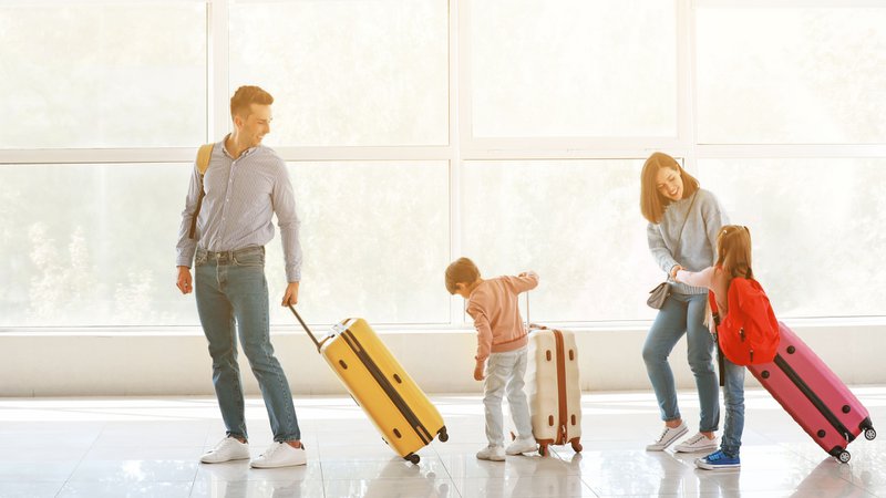 deux enfants accompagnés de leurs parents dans un aéroport, avec leurs bagages.
