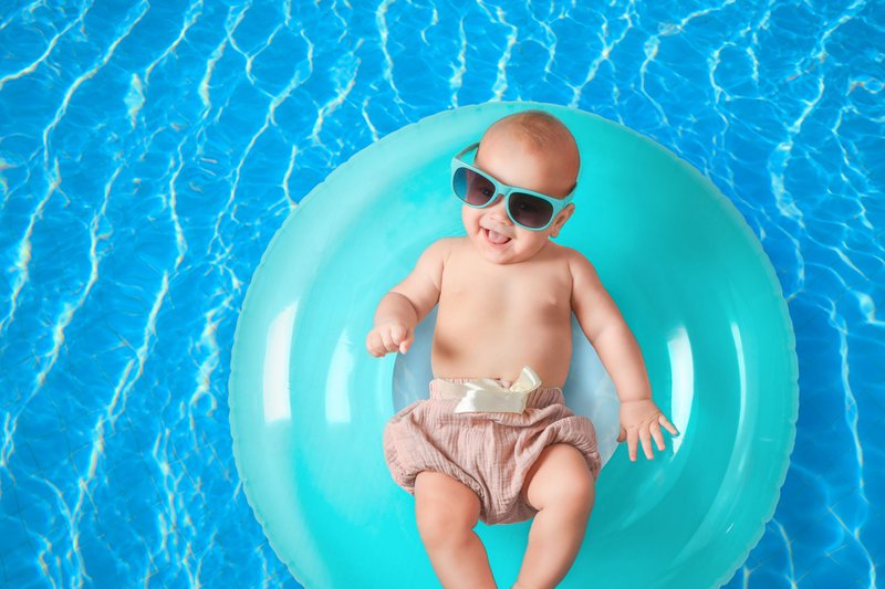 Un bébé en vacances dans une eau turquoise, dans une bouée bleue