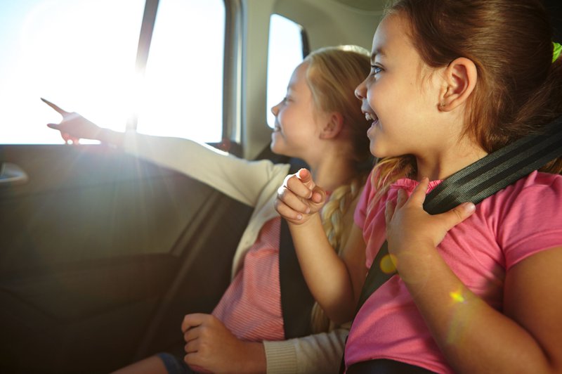 twee kinderen op de achterbank van een auto met hun gordels aan