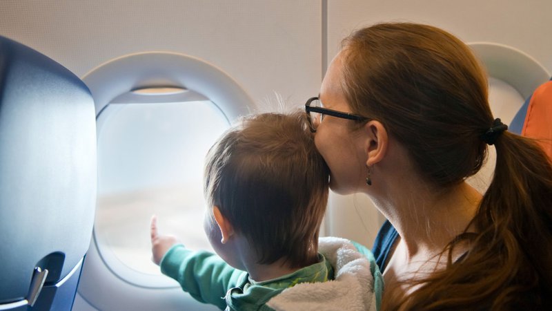 Un enfant sans écran et un parent qui regardent à travers le hublot dans un avion
