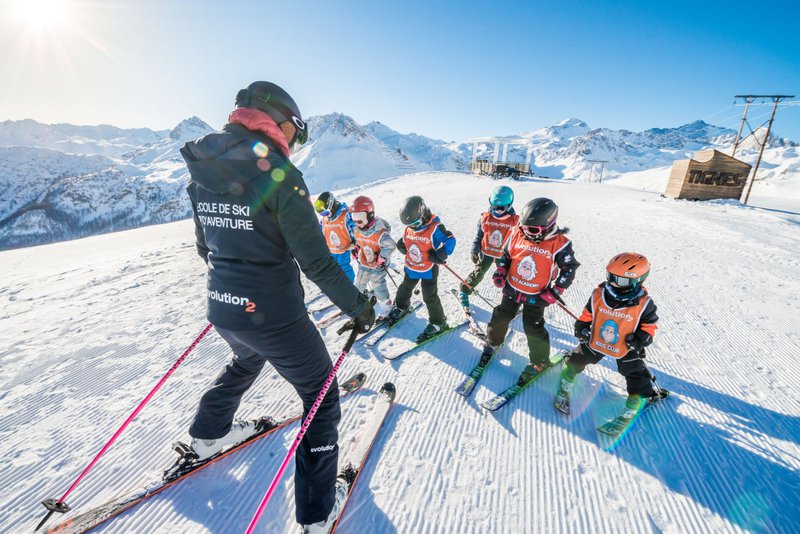 6 enfants apprennent à skier en altitude sur les montagnes enneigées.