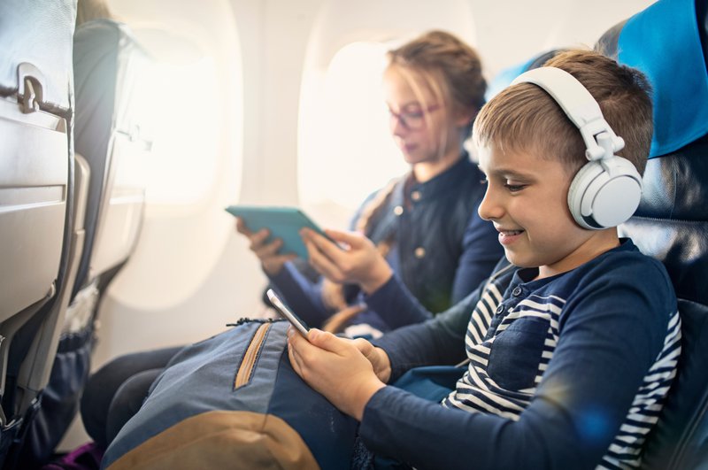 Deux enfants avec des tablettes à bord d'un avion.