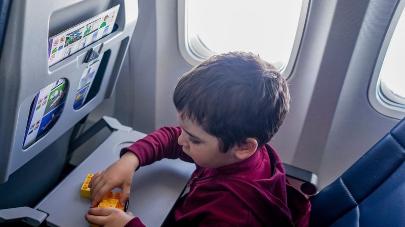 Un enfant, sans écran, joue avec des blocs dans un avion