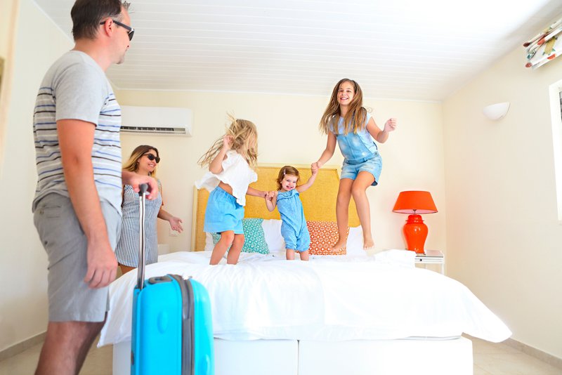 Des enfants jouent sur un lit dans un hôtel familial sous le regard des parents