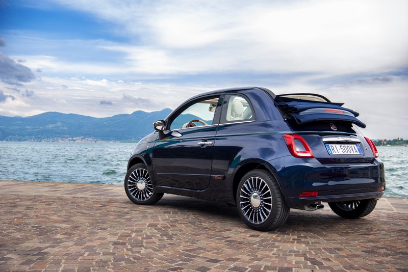 Fiat 500 bleu marine décapotée et vue de l'arrière sur une plage devant la mer.