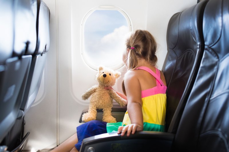 Un enfant avec une peluche dans un siège d'avion