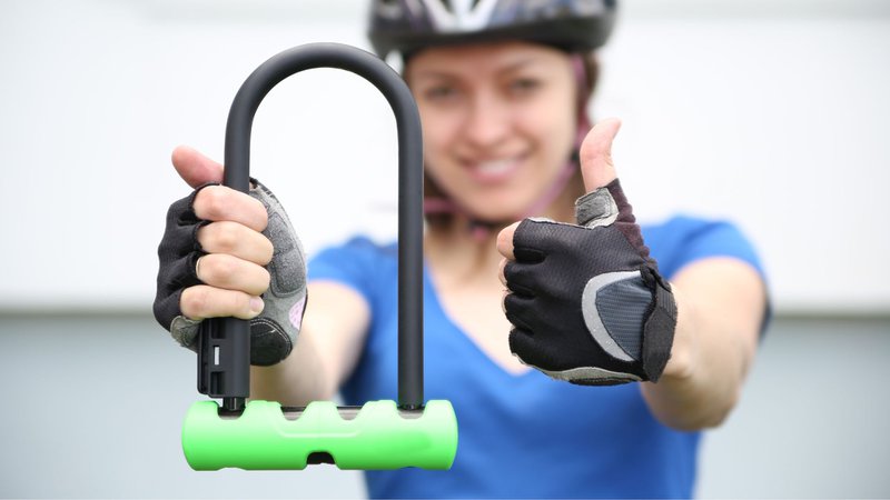 Une femme montre un cadenas à arceau et lève le pouce en signe d'approbation.