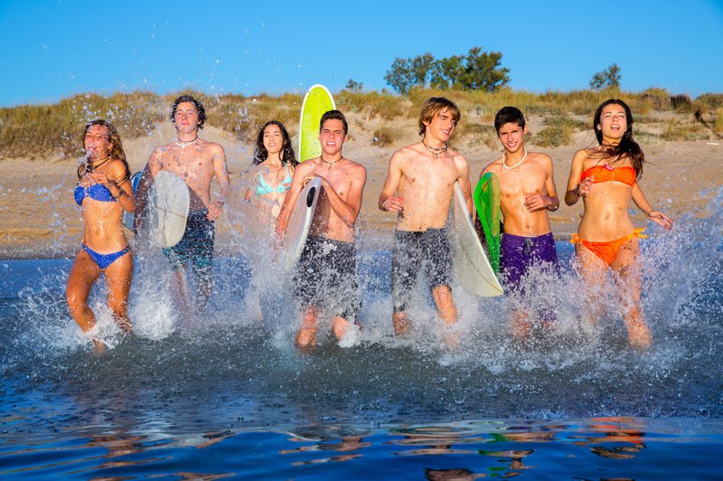 Des adolescents munis de planches de surf se jettent à l'eau