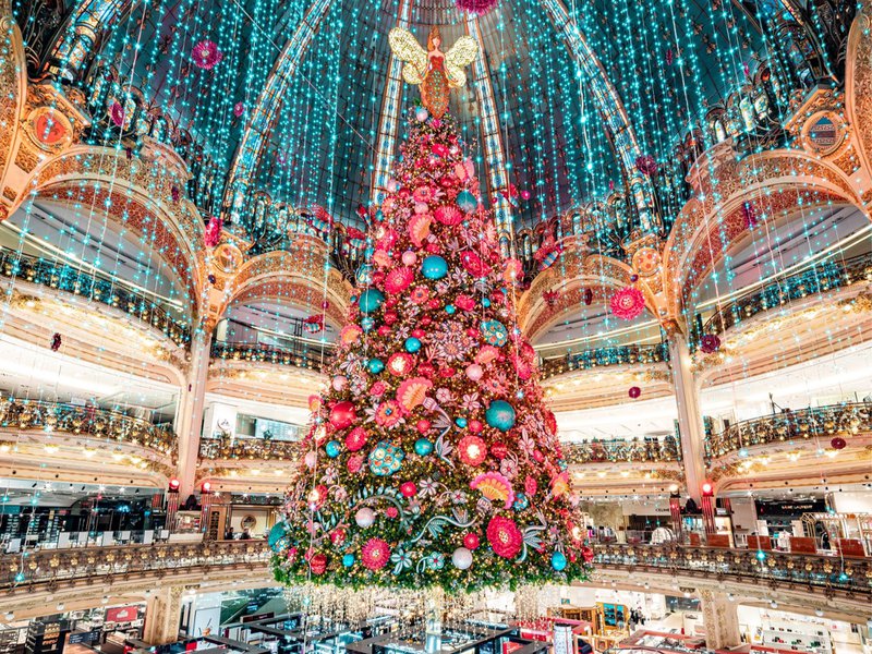 Gigantesque sapin de Noël dans un centre commercial richement décoré d'innombrables lumières colorées.