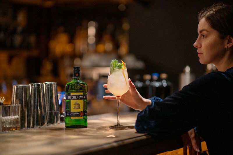 une femme assise à un bar tenant une boisson