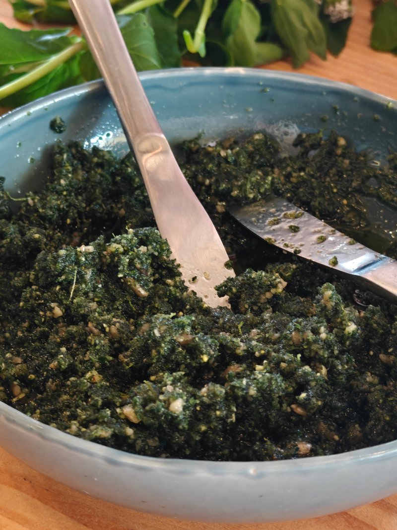 groene tapenade van zelfgeplukte planen in een bordje met twee messen