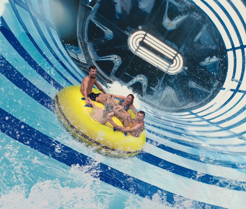 Toboggan aquatique avec énorme bouée gonflable remplie de gens.