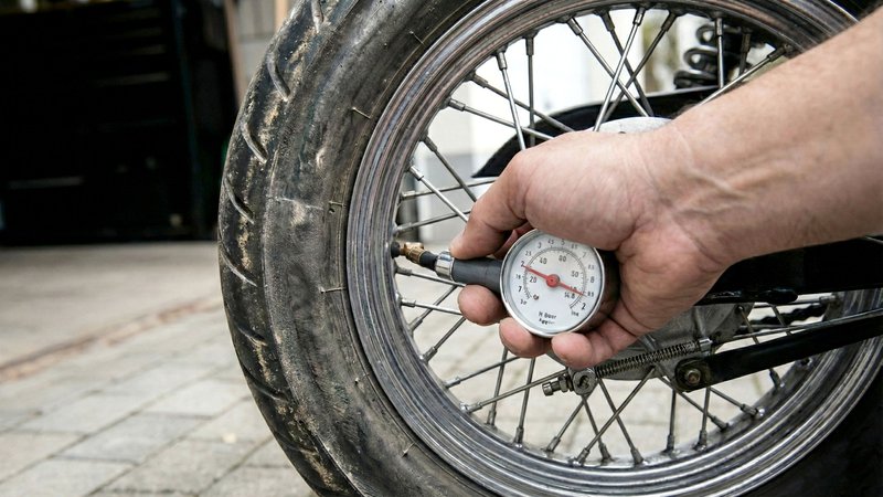 Motorrijder controleert bandenspanning met meter na winterstalling