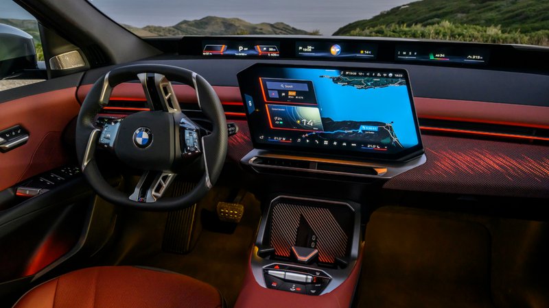 Habitacle du BMW iX3 avec grand écran central, bandeau d’affichage panoramique et sellerie brun rouge.
