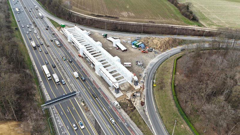photo aérienne d'un chantier le long de l'autoroute - pont en arc métallique en construction près d'une sortie.