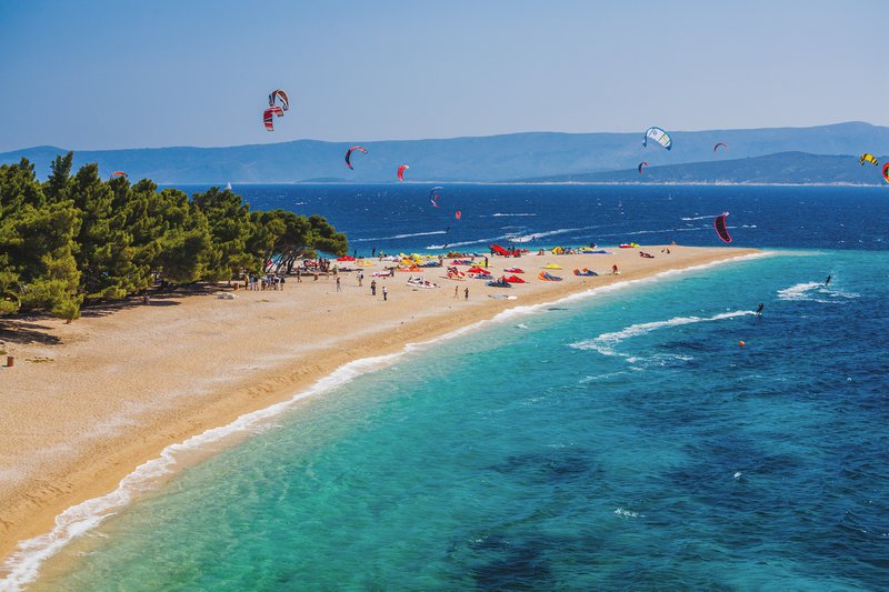 luchtfoto strand met surfers en paragliders op een stralende zomerdag