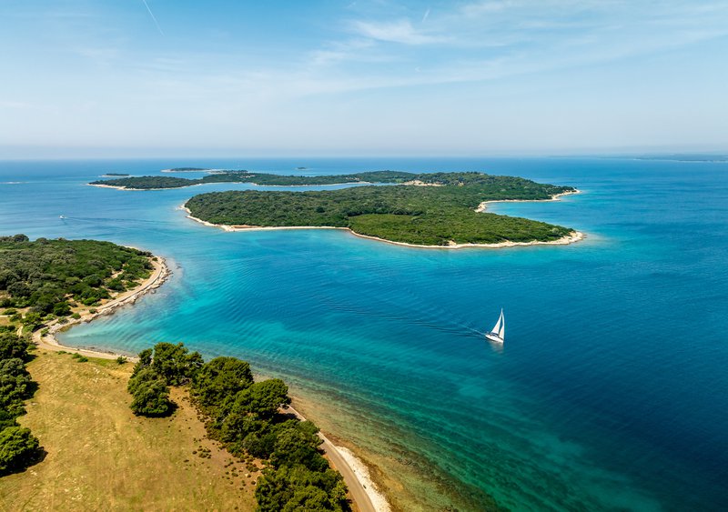 eenzame zeilboot op azuurblauwe zee met eilandjes in Kroatië