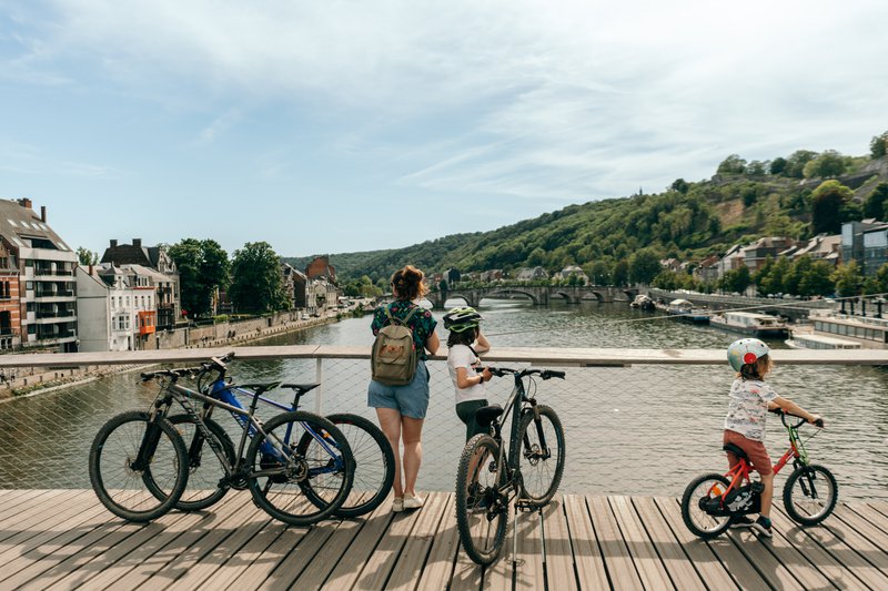 Drie jonge fietsers op een houten brug over de Maas in Namen.